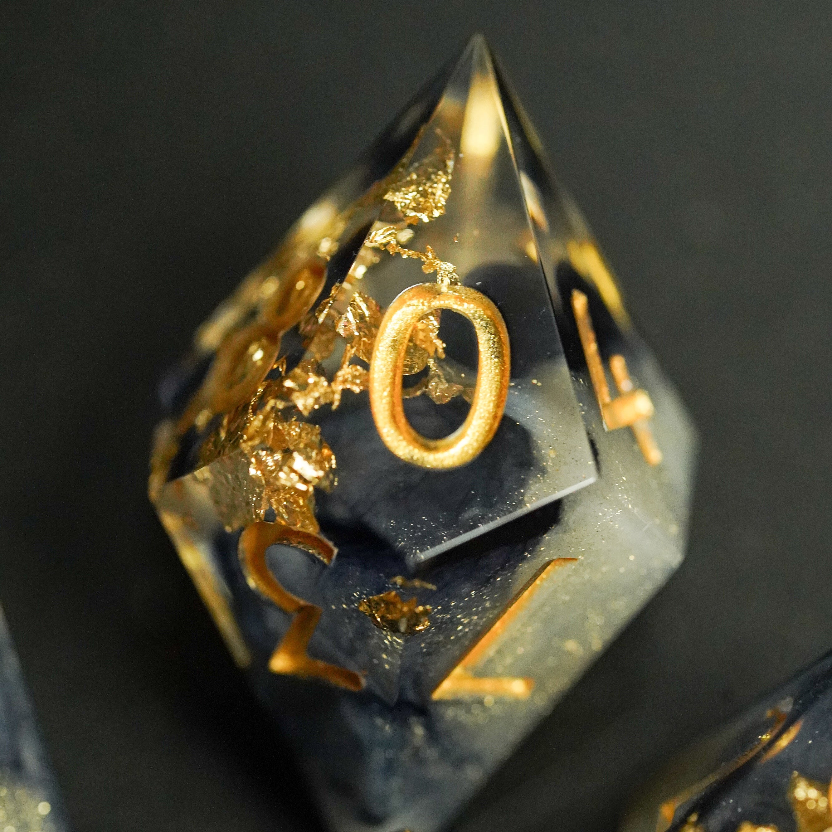 Decorative polyhedral dice with gold embellishments on a dark background