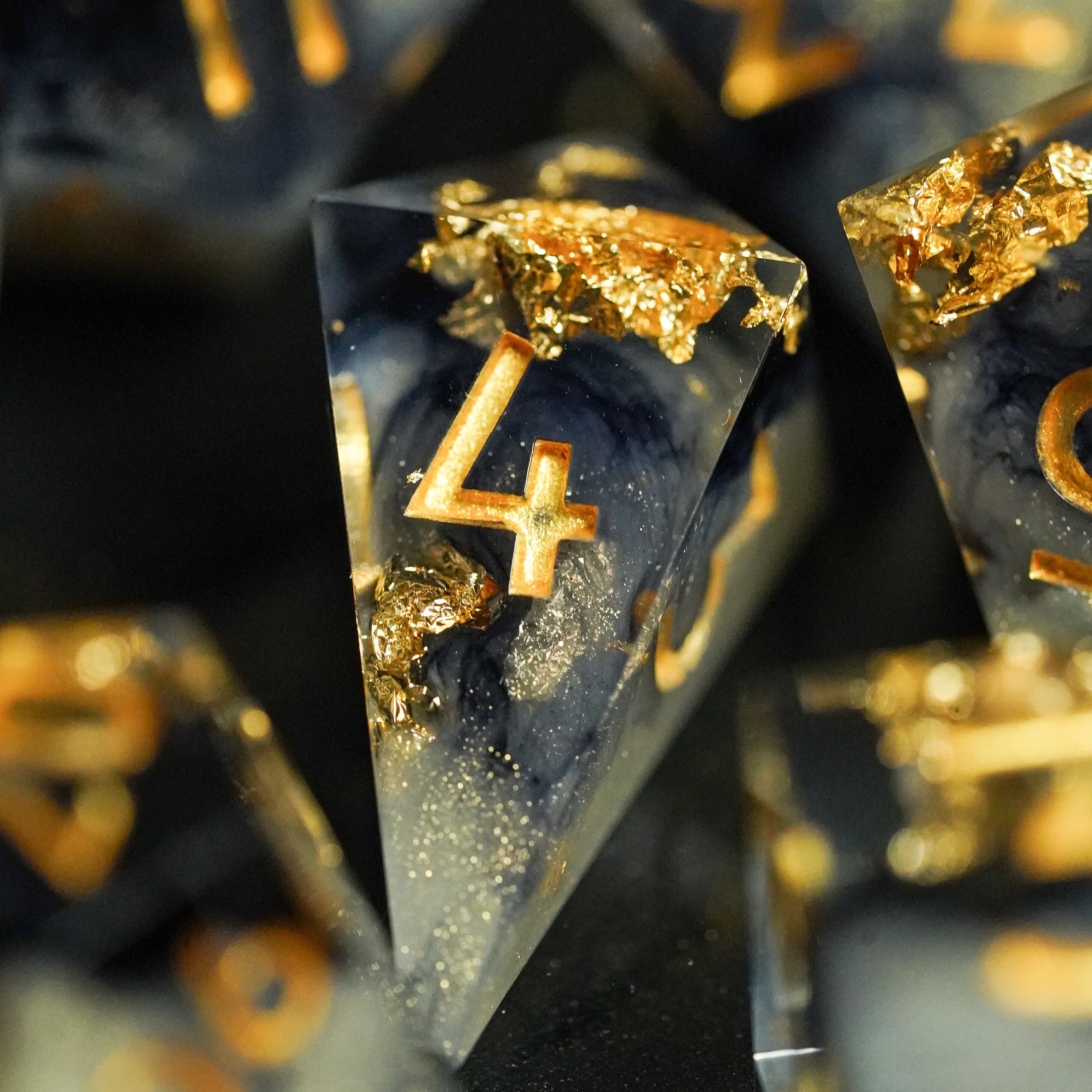 Clear resin objects with gold numbers and embellishments on a dark background