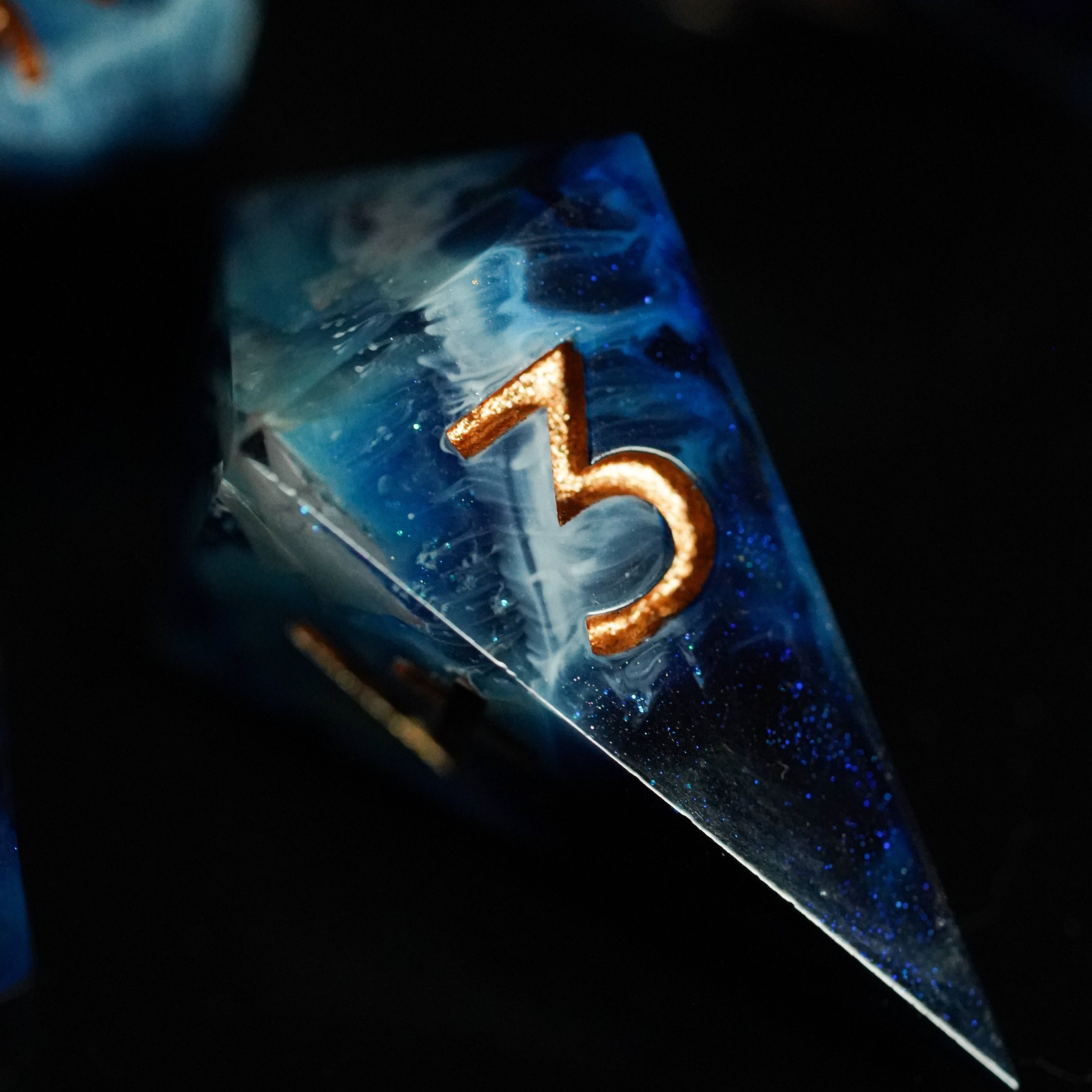 Close-up of a blue transparent die with the number 3 on it, against a dark background.