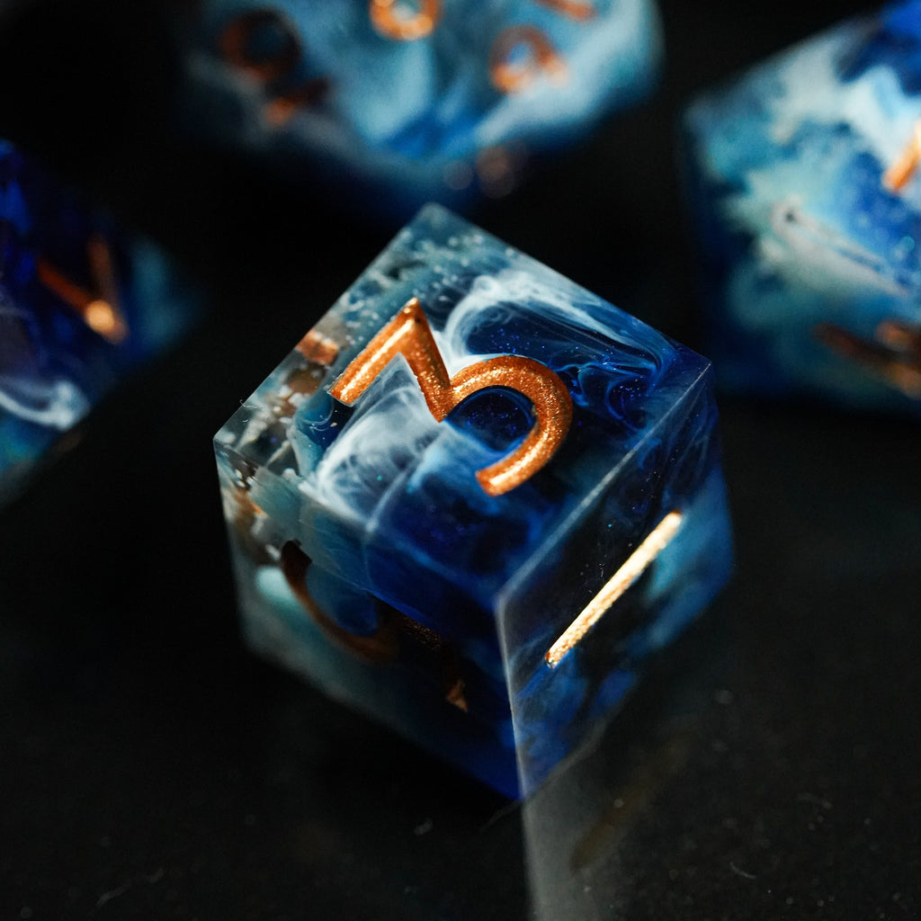 Close-up of blue dice with orange numbers on a dark surface