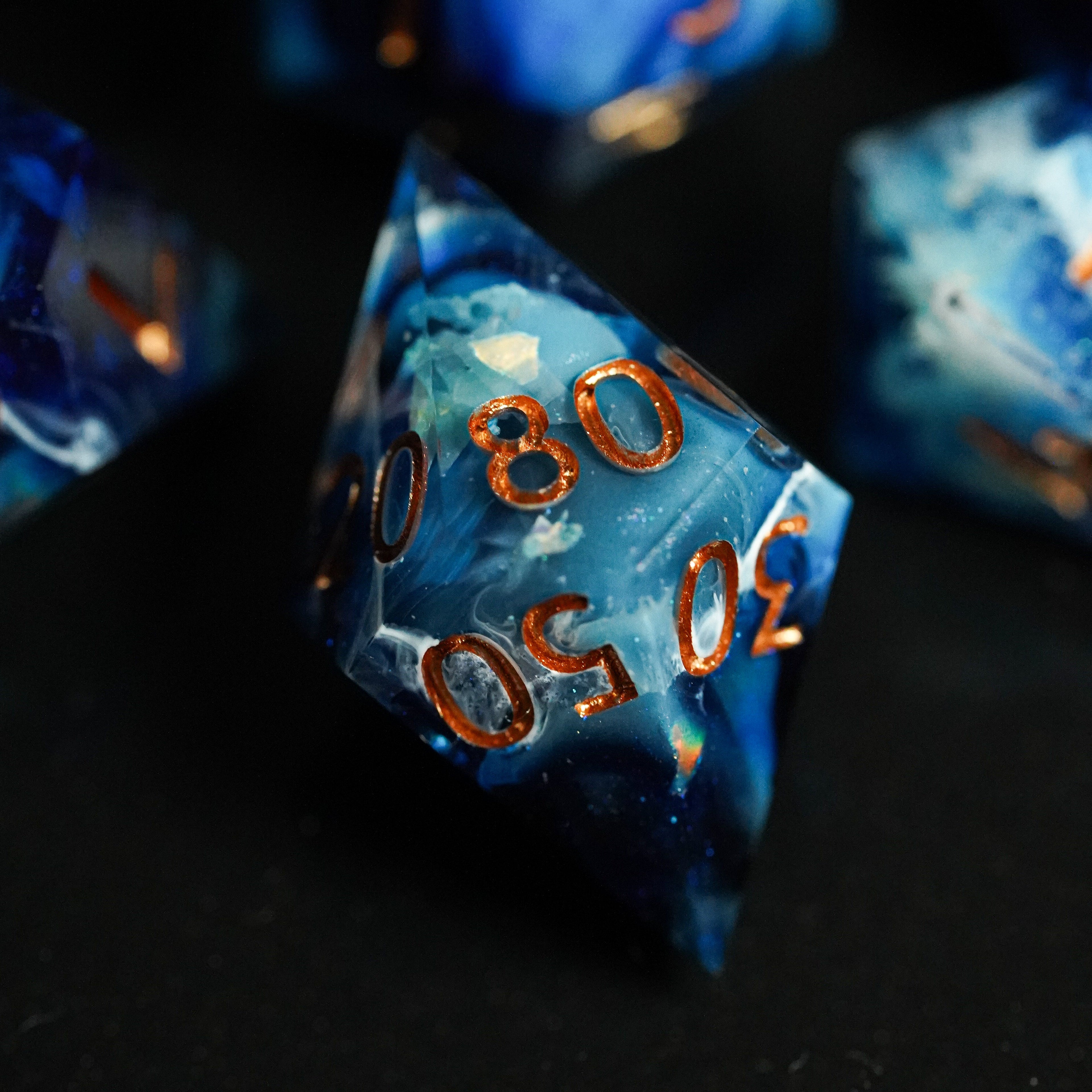 Close-up of blue polyhedral dice with copper numbers on a black background