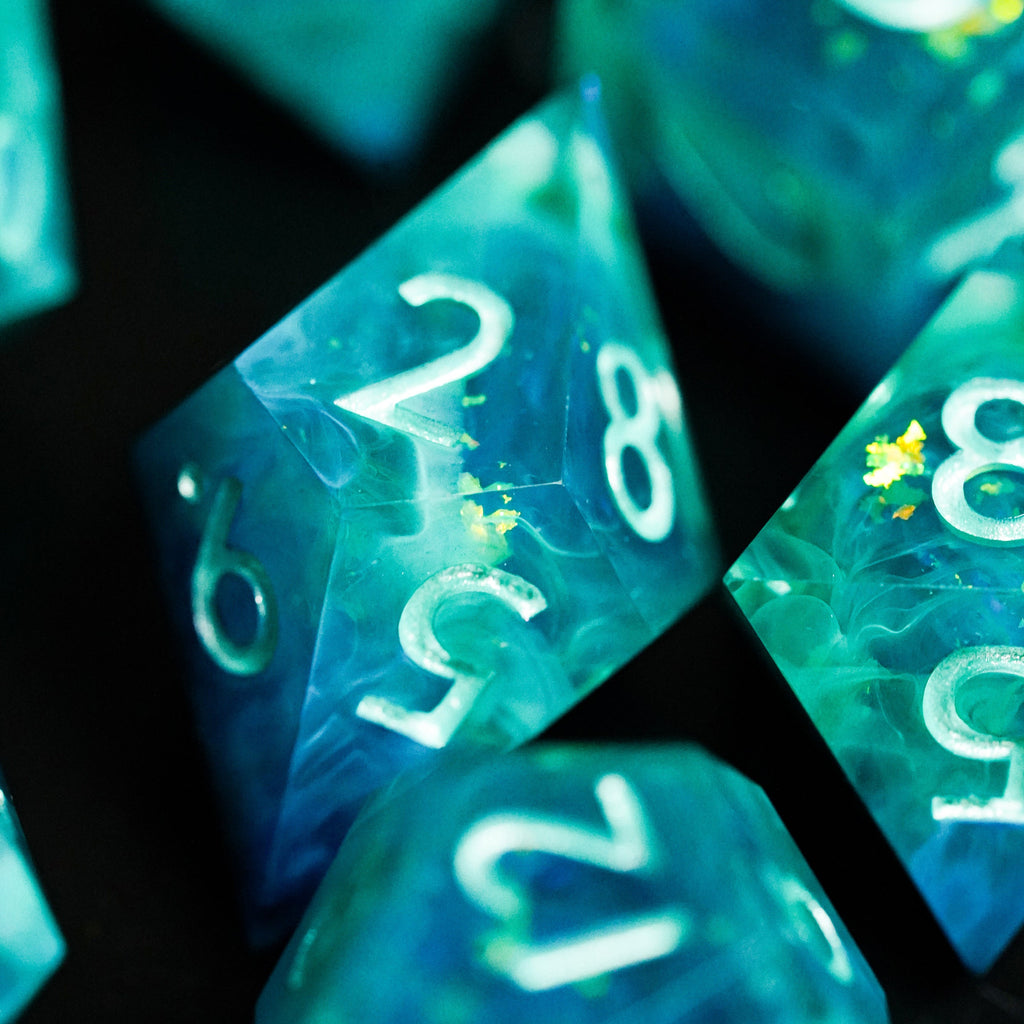 Close-up of teal polyhedral dice with white numbers on a black background