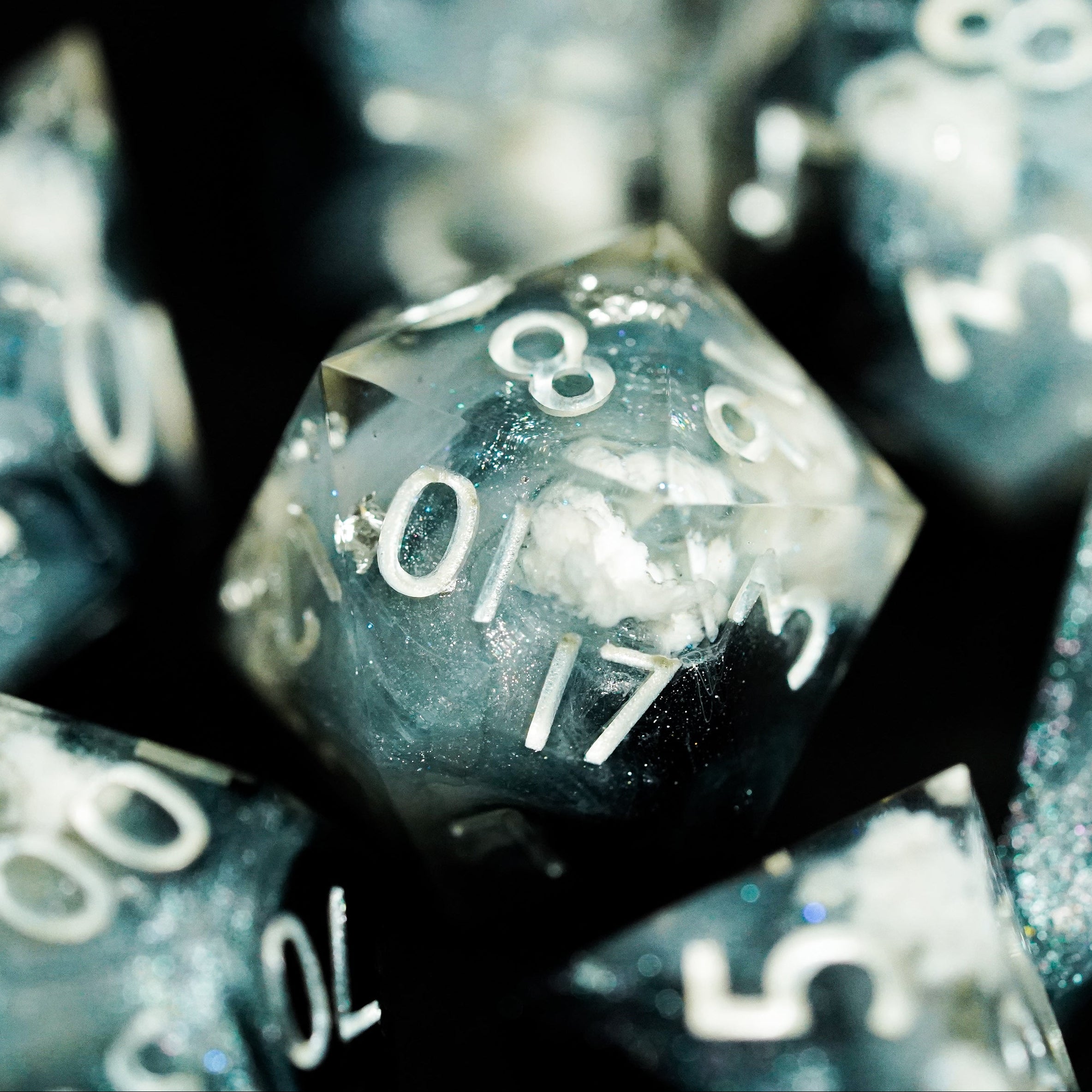 Close-up of multiple polyhedral dice with numbers on a dark background