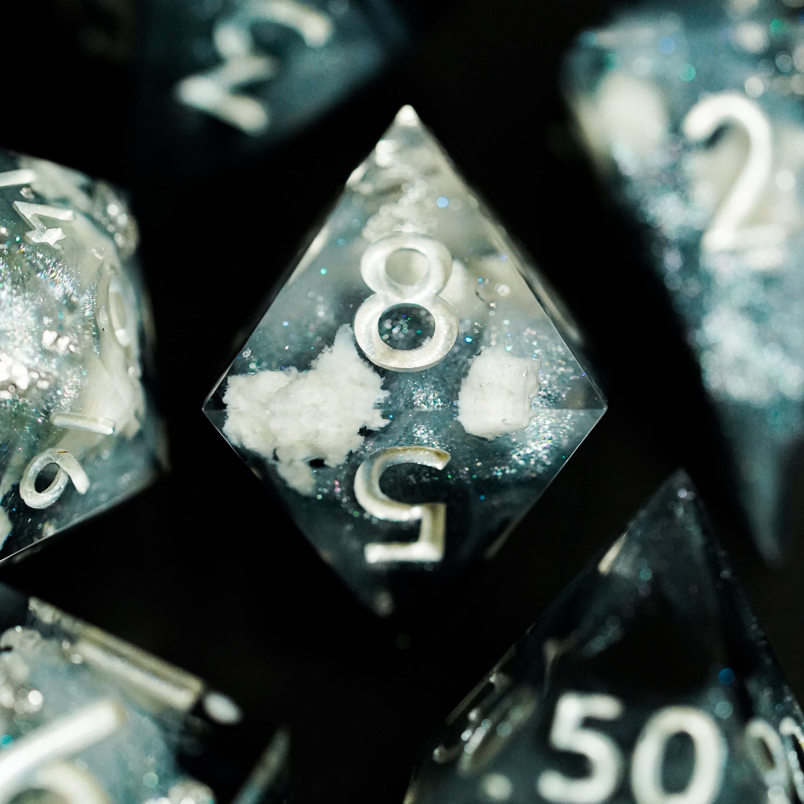 Close-up of clear dice with silver numbers on a black background
